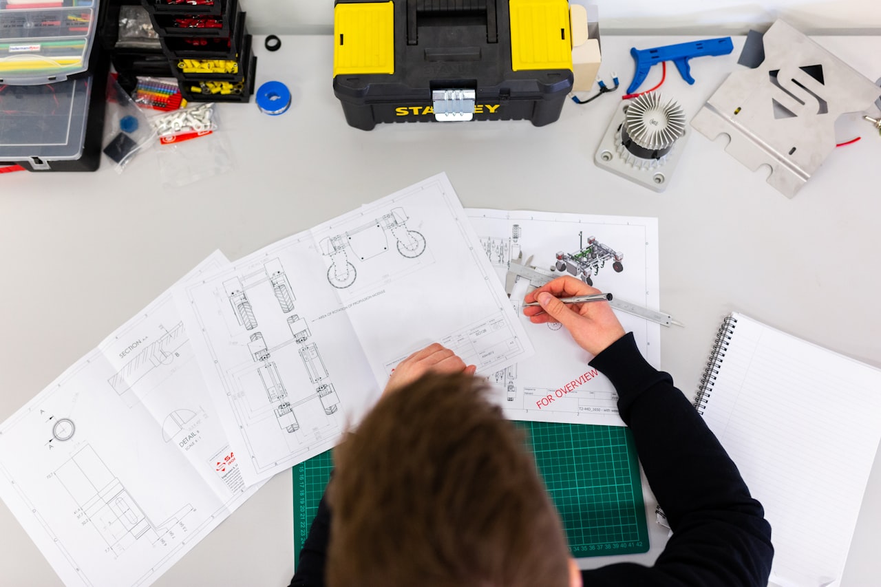 Technical drawings, measurement instruments and notebook on a desk during a documentation review